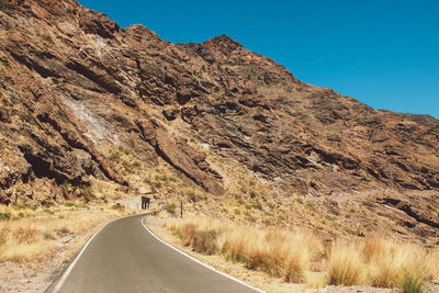 Road passing through mountain against clear sky