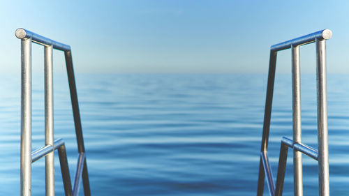 Close-up of metal railing by sea against sky