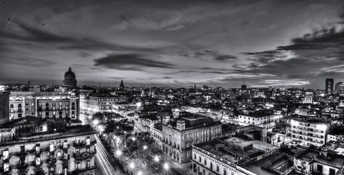 High angle view of city lit up against cloudy sky