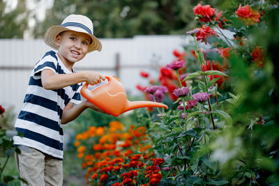 Cute little boy watering flowers with a watering can on a sunny summer day