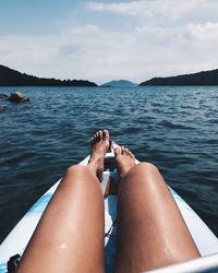 Low section of woman sitting on sea against sky