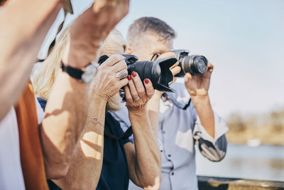 Side view of senior friends using cameras at park