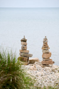 Stack of stones in sea against sky