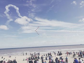 People at beach looking in sky during airshow