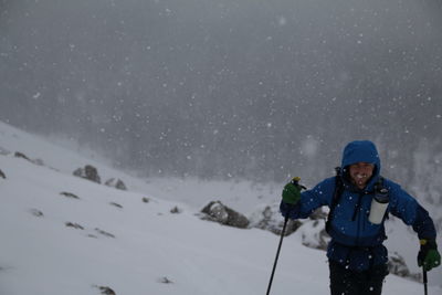 Portrait of man skiing on snow covered mountain against sky