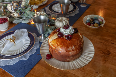 Panettone bread with cherries and whipped cream on a holiday table at christmas.