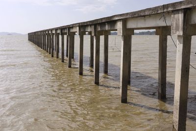 Wooden posts on beach by sea against sky