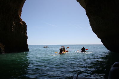 People kayaking on sea against sky