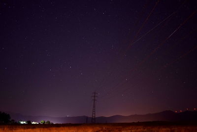 Low angle view of electricity pylon against sky at night