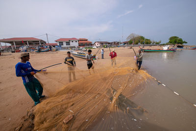 People on shore against sky