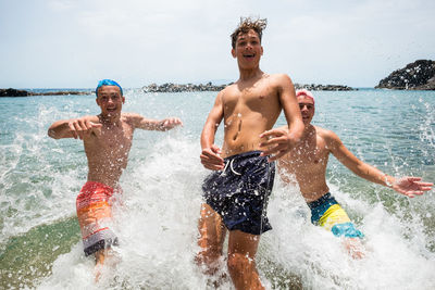 Full length of shirtless man splashing water in sea