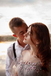 A beautiful wedding couple on the riverbank at sunset.