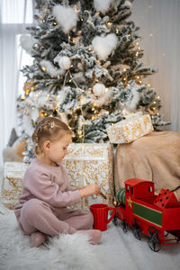 Cute girl playing with christmas tree at home