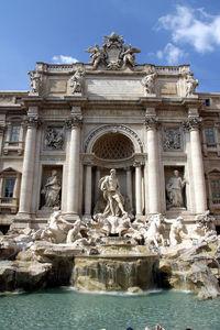 Statues on fountain in front of historical building