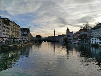 View of town at waterfront against cloudy sky