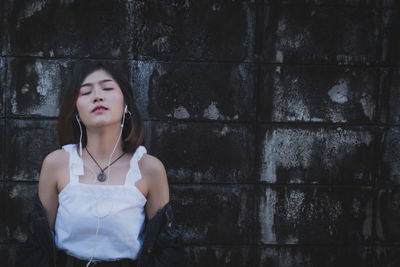 Thoughtful young woman standing against wall