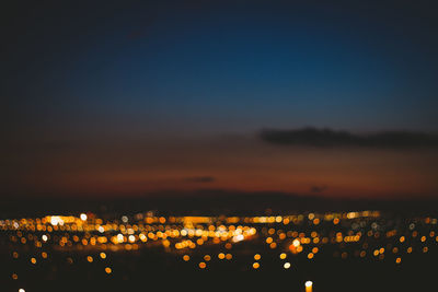 Defocused image of illuminated cityscape against sky at night