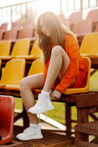 A teenage girl ties her shoelaces in sneakers, prepares for training