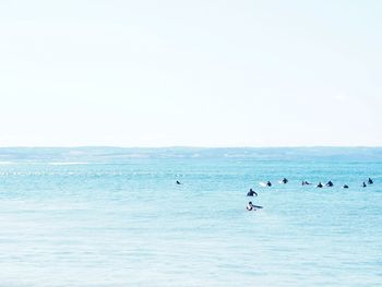 People in sea against clear sky