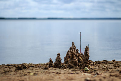 Close-up of sand castle by lake against sky