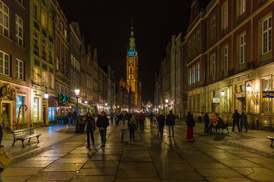 People at illuminated town square against clock tower