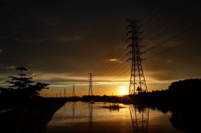 Silhouette trees and electricity pylon against sky during sunset