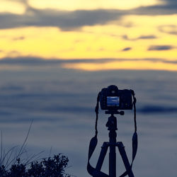 View of camera against sea during sunset