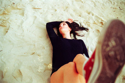 High angle view of young woman lying on sandy beach