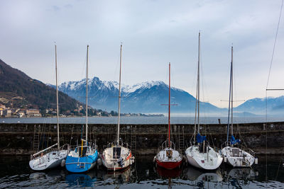 Sailboats moored in sea against sky