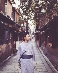 Thoughtful young man wearing traditional clothing while standing in alley