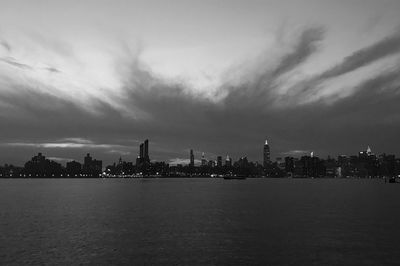 City at waterfront against cloudy sky