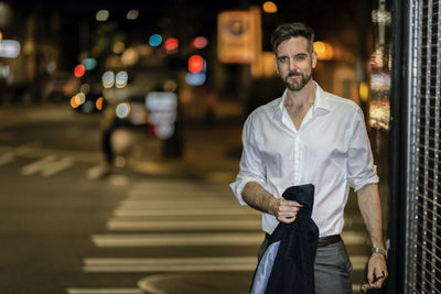 Portrait of handsome man standing on street in city