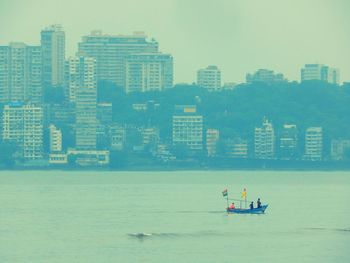 Man in sea by city against sky