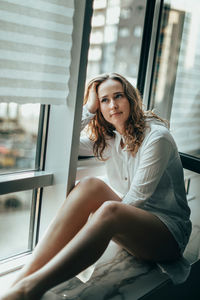 Young woman sitting on window