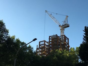 Low angle view of crane against clear blue sky