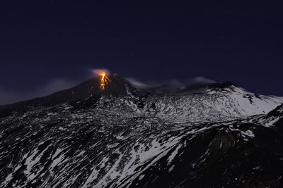 Scenic view of snowcapped mountains against sky at night