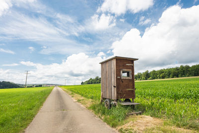 Portable toilet by road on field against sky