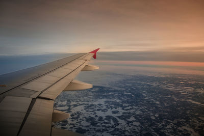 Close-up of airplane flying over landscape against sky