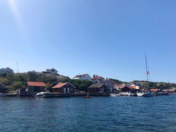 Houses by sea against clear sky