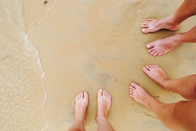 Low section of friends standing on shore at beach