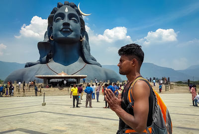 People at statue against sky