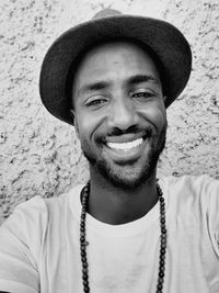 Portrait of smiling man wearing hat against wall