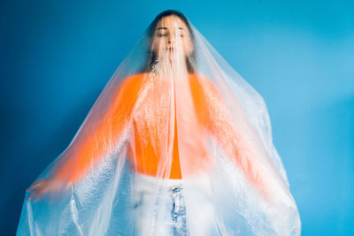 Woman covered in plastic standing against blue background