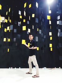 Portrait of young man standing against illuminated wall