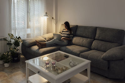 Woman using laptop on sofa at home