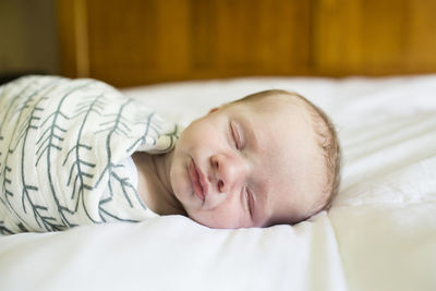 Close-up of baby boy sleeping on bed at home