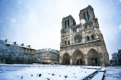 Low angle view of snow covered building against sky