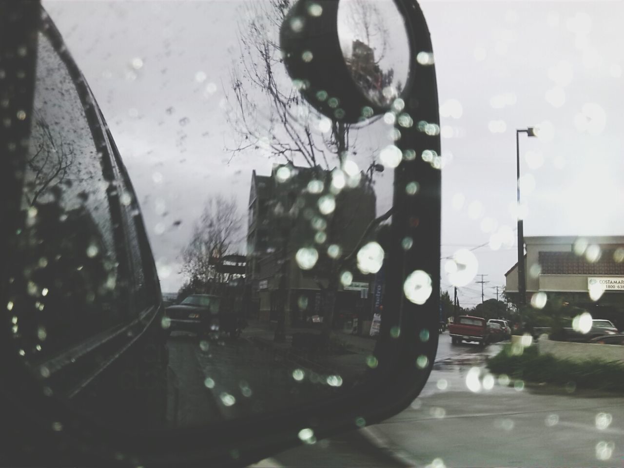 wet, glass - material, rain, transparent, window, architecture, building exterior, drop, water, built structure, reflection, illuminated, street, city, sky, car, indoors, transportation, raindrop, land vehicle