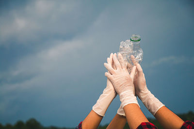 Low section of people holding glass against sky