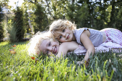 Portrait of sisters lying on grassy field at park